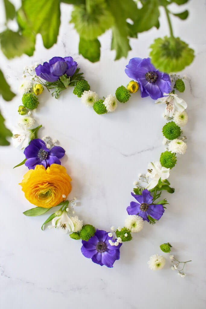 Couronne de fleurs formant un coeur sur fond marbre
