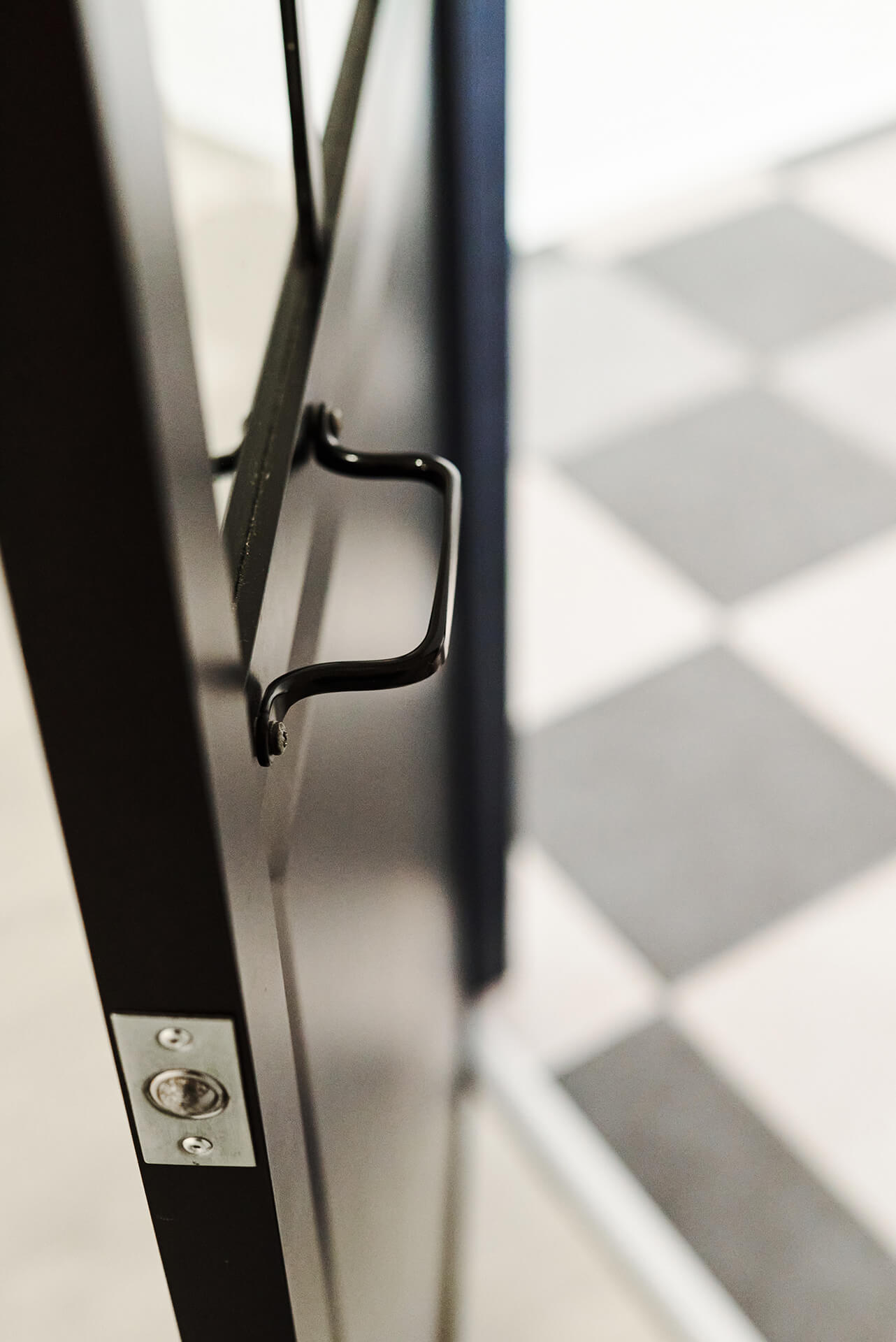 détail porte métallique et sol carrelage damier dans loft moderne noir et blanc