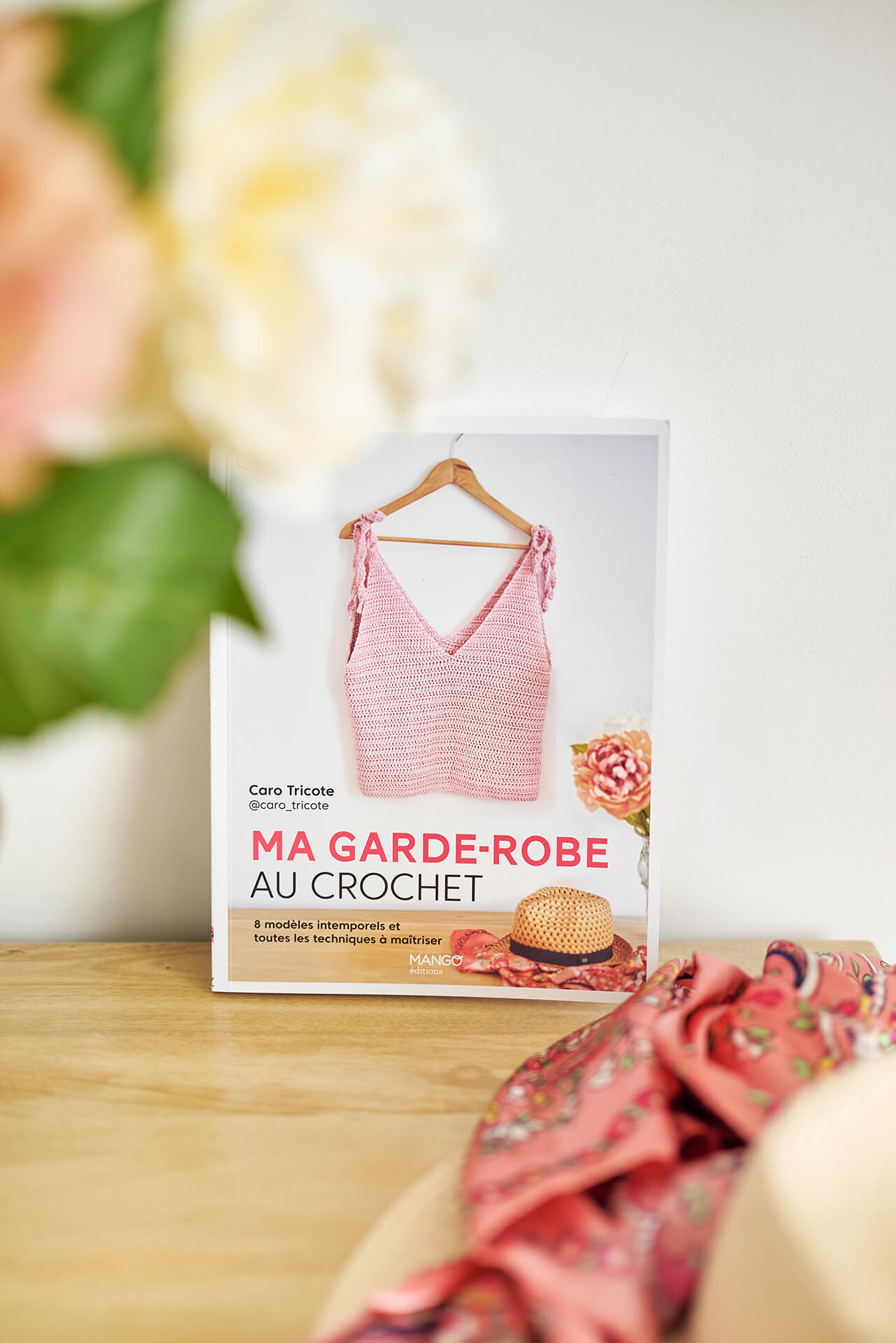 Livre "ma garde robe au crochet" de Caro Tricote posé sur commande avec foulard et fleurs